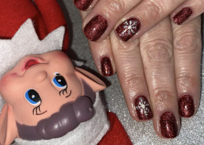 "Elf on the shelf" next to freshly painted burgundy nails with snow flake design.